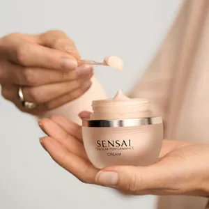 Personne utilisant une spatule pour prélever le produit Cellular Performance Crème dans un pot